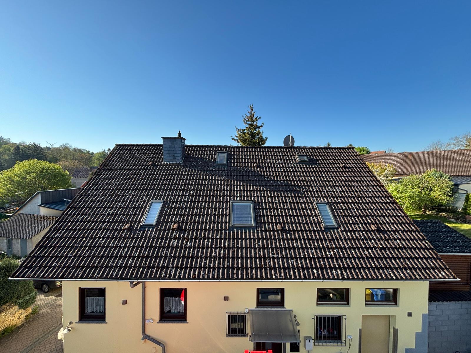 Doppelhaus mit Tonziegeln vor der Dachreinigung, deutlich vermoost
